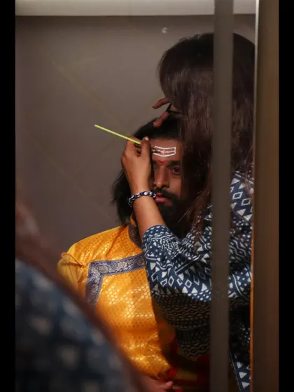A close-up of the 'tilak' being applied, seen through a mirror. This creative angle provides an intimate, behind-the-scenes perspective on the transformation.