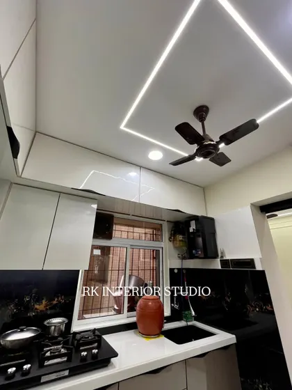This kitchen features a stunning black patterned backsplash that contrasts beautifully with the white countertops and cabinets. The profile lighting in the ceiling provides excellent, even illumination.