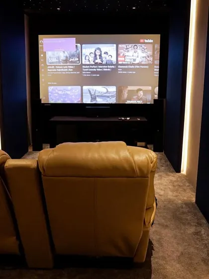 A compact luxury home cinema in Thoothukudi, featuring two plush leather recliners, a starlit ceiling, and a simple, elegant wall design.