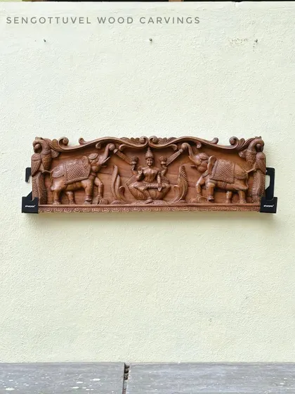 Our 36-inch Gajalakshmi panel, featuring the goddess flanked by two elephants, is shown mounted on a wall. The natural wood finish offers a timeless and elegant look for any space.