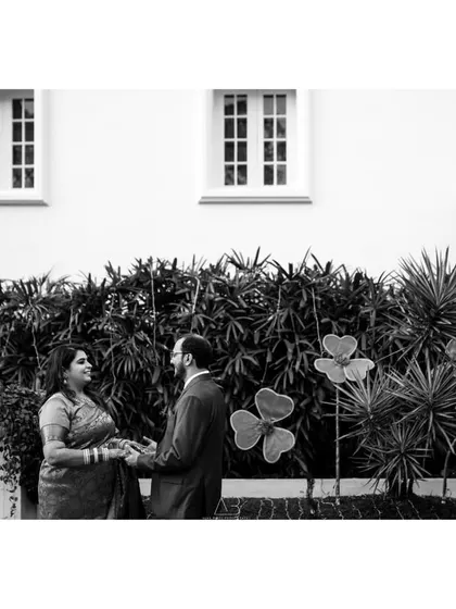 A wide shot of a couple sharing a moment, framed by the architecture and greenery. This black and white image has a timeless, classic feel.