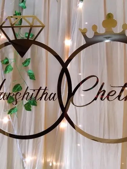 A custom acrylic sign with the couple's names inside interlocking rings, used as a personalized detail on an engagement backdrop.