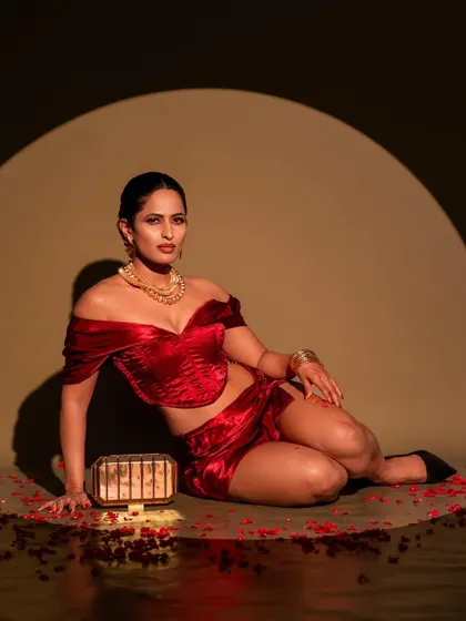 A full-body shot from the same red velvet series, set against a spotlight. This pose highlights the complete outfit and creates a classic, old-Hollywood feel with a modern twist.