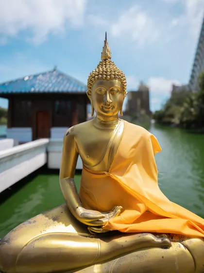 A close-up of a golden Buddha statue at the Gangaramaya Temple in Colombo. The vibrant colors and serene expression make for a powerful and peaceful image.