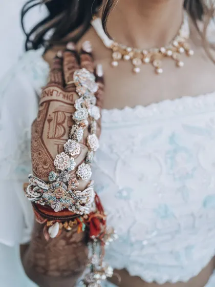 A close-up shot of the bride's intricate floral hand jewelry and henna design.