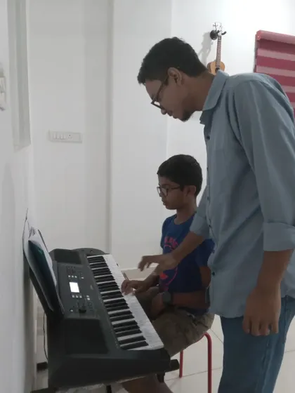 An instructor guiding a young student's hands on the keyboard. We make learning accessible and fun for our youngest musicians.