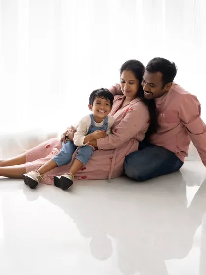 A relaxed and loving family portrait on the floor. The reflection on the glossy floor adds a beautiful artistic touch.