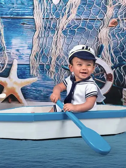 All aboard! This little sailor is ready to set sail in our adorable nautical-themed studio setup, complete with a sailor suit, boat, and anchor.