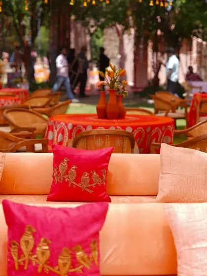 We ensure every seating area is thoughtfully styled. This lounge sofa is adorned with custom embroidered cushions in bright pink and orange, perfectly complementing the Haldi theme.
