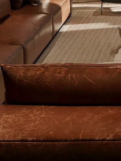A close-up of the distressed leather sofa, showcasing the beauty of natural materials. The texture adds a layer of warmth and character to this leisure space.