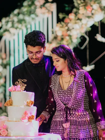 The couple cutting their elegant three-tiered cake, a sweet moment from their modern reception.