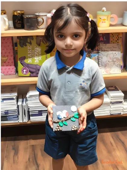 A young girl holds up her clay art project, a cute depiction of two birds on a branch, made during a field trip to my studio.