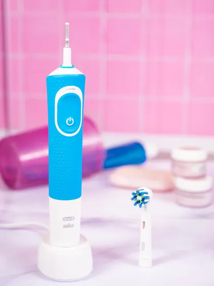 This lifestyle shot for the Oral-B electric toothbrush places it in a bathroom setting. The bright, clean colors reinforce the product's purpose of hygiene and health.