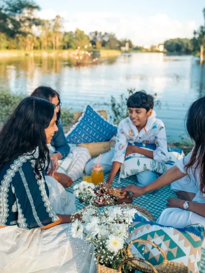 A happy picnic scene by the lake, made more comfortable with our collection of blue and white cushion covers. They are perfect for adding a touch of style to outdoor gatherings.