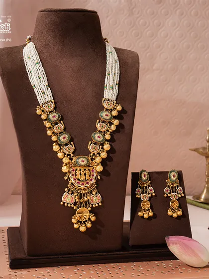 A wider view of the majestic Rajnitya Haar, showcasing its full length and the accompanying earrings. The multi-strand pearl chain adds a layer of softness to the ornate gold pendant, creating a perfectly balanced piece of royal adornment.