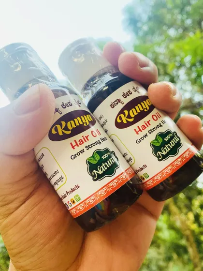 Holding two bottles of my hair oil. The one on the left shows the ingredients list, which includes Amla, Brahmi, and Hibiscus.
