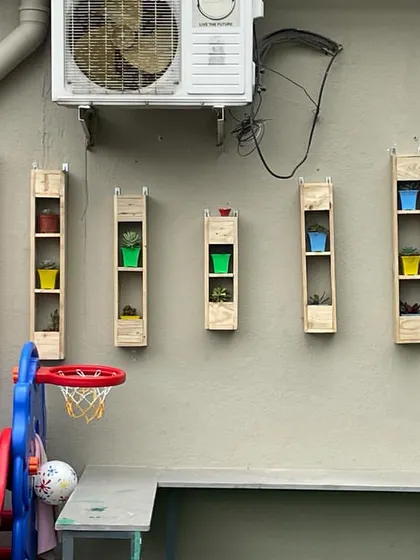 This image shows a custom vertical shelving solution for displaying small potted plants, adding a touch of color and life to a previously bare wall on a terrace.
