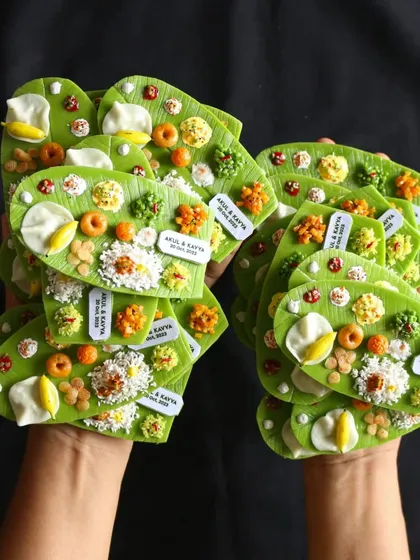 Holding a collection of custom-made South Indian meal magnets for a wedding. These personalized return gifts are a unique way to celebrate a special day.