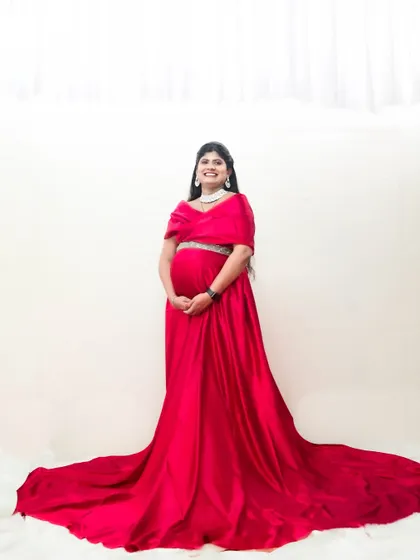 This red satin two-piece gown is a modern and elegant choice for maternity shoots, showing off the baby bump beautifully.
