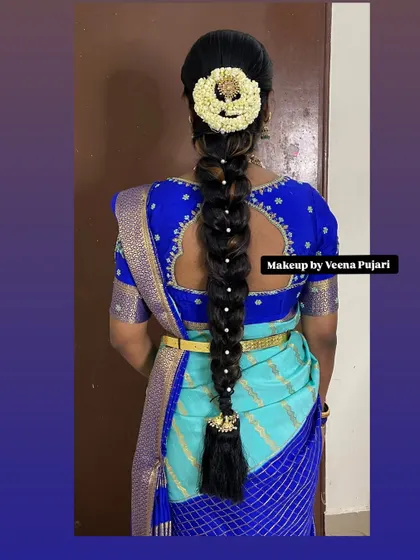 A neat and traditional bridal braid decorated with pearl-studded pins and a floral veni. This hairstyle is perfect for keeping hair elegantly in place during long ceremonies.