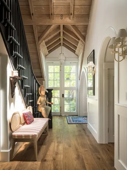 The entryway of the Saratoga home, where a 'Devi' sculpture sits at the foot of the black-painted staircase. This space immediately establishes the home's unique blend of contemporary design and Indian cultural elements.
