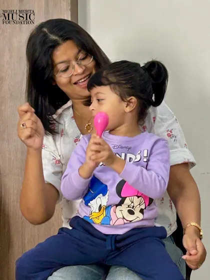 Our early-years certification covers teaching even the youngest learners. This photo shows a teacher guiding a toddler with a maraca, demonstrating how we create a nurturing musical bond between the instructor, the child, and sometimes the parent, right from the start.