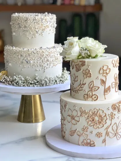 Here are two beautiful options for an intimate white wedding. One features delicate hand-piped and gold-painted floral details, while the other is adorned with a cascade of sparkling sprinkles. Both are 3.5 kilos and completely eggless.