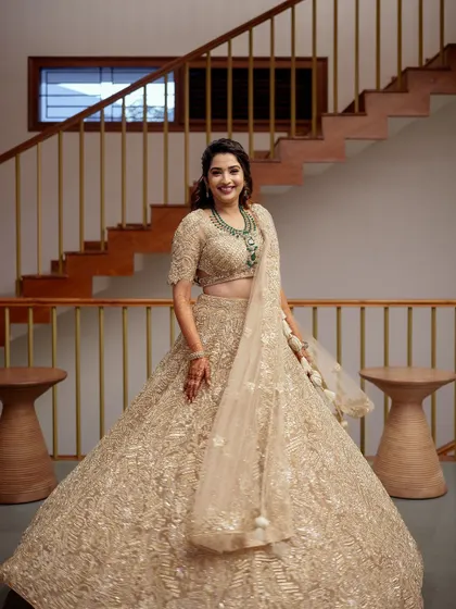 A full-length view of the bride in her stunning golden lehenga, showcasing the magnificent flare and detailed craftsmanship of the skirt.