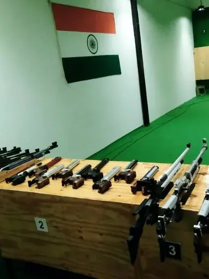 A view of the shooting lanes from behind our collection of air rifles. The green flooring and wood paneling create a professional and focused atmosphere.