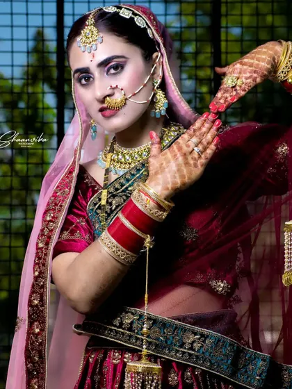 A beautiful portrait of the bride, her hands framing her face in a classic pose that highlights her mehndi and jewelry.