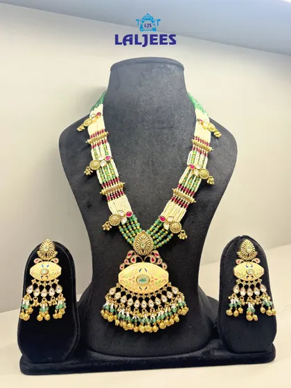 A beautiful long necklace set, also known as a rani haar, with intricate work and green bead detailing. Perfect for layering over a choker.
