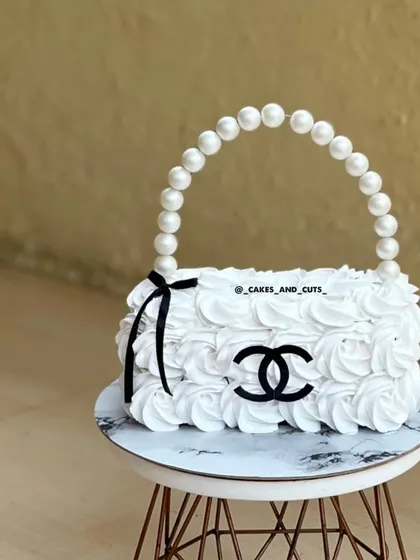 A close-up of our sculpted purse cake, showing the rosette piping detail and the iconic logo.