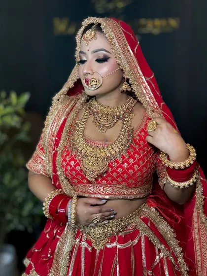 A close-up of a bride in her red and gold attire. Her makeup is bold and beautiful, with a focus on dramatic eyes and a perfectly contoured face.
