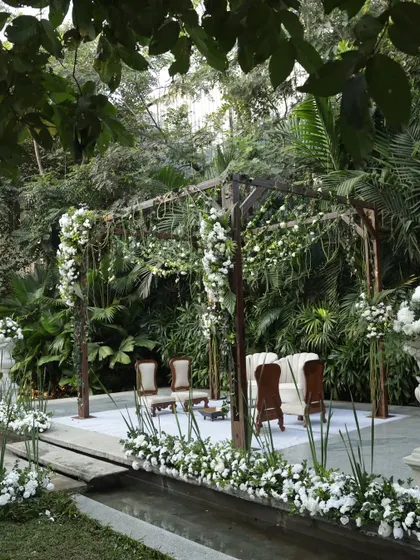A wide shot of the elegant white and green ceremony setup, showing the aisle and stage surrounded by nature.