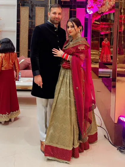 A beautiful outfit for a new bride. This lehenga combines a traditional silhouette with modern design elements, featuring a rich red dupatta and a patterned skirt.