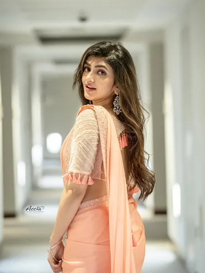 A full-length shot in a hallway creates leading lines that draw the eye to the subject. The pose is elegant and the lighting is soft, making for a beautiful indoor portrait.