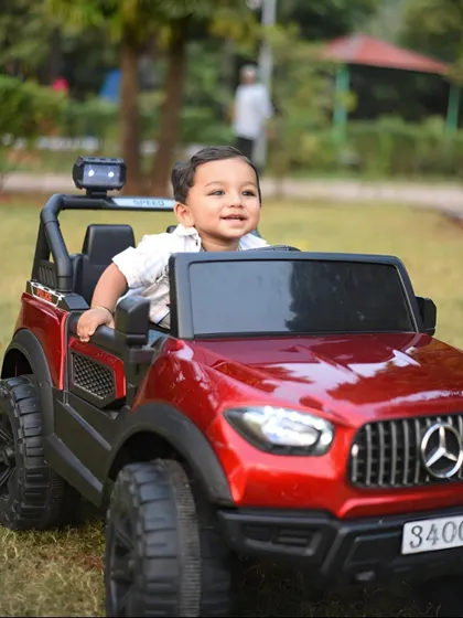 A happy, smiling portrait of the little boy enjoying his toy jeep in the park.