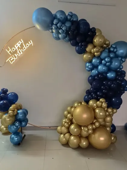 A full view of the navy and gold balloon arch on a copper ring with a neon sign.