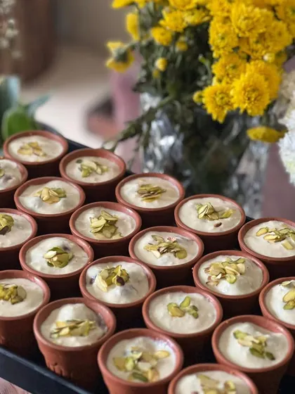 A tray of our delicious Phirni, served in individual terracotta bowls, ready for a festive gathering.