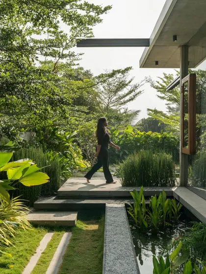 A stone pathway meanders through the lush garden and alongside a water channel at The Quarry House, inviting a tranquil walk around the property.