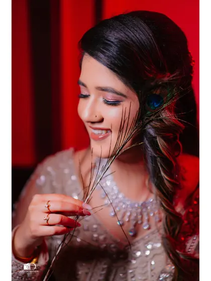 A close-up candid shot capturing the bride's genuine smile. The peacock feather adds a touch of unique detail, making this a personal and joyful portrait from her wedding day.