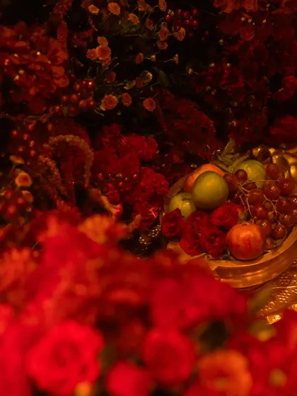 A close up of the rich textures in our all red decor. We used a variety of flowers and even incorporated fresh fruits like grapes and apples in golden bowls to add depth and a touch of classic still life beauty.