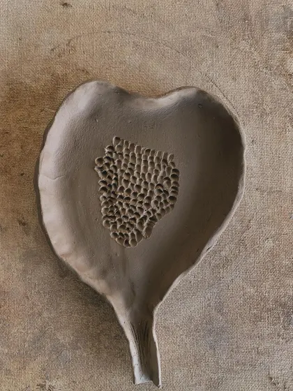 A raw clay leaf dish, with a textured center. This piece is waiting for the fire to transform it, but it already holds so much beauty in its natural, earthy state.