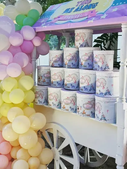 A cart filled with custom-branded party favors, perfectly matching the pastel carnival theme.