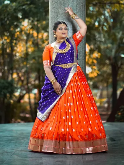 This client is rocking her bold orange and blue half saree, a perfect look for dandiya nights.