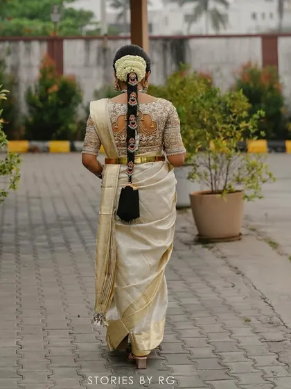 The back view of Harshitha's bridal attire, showing the beautiful floral hair arrangement and the intricate work on her blouse.