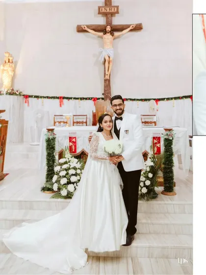 A formal portrait of the couple at the altar. The bride's elegant gown with its long train looks stunning against the backdrop of the church's crucifix and the simple white floral arrangements.
