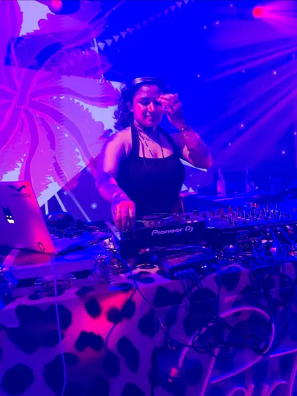 Mixing under cool blue and purple lights with psychedelic visuals in the background for a private event.