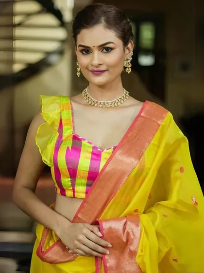 This model wears a bright, multi-colored checkered blouse with a simple gold choker, creating a playful and vibrant look.