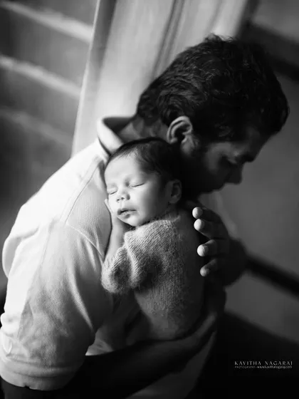 A father holds his sleeping newborn, a quiet moment of connection captured in dramatic black and white. A tribute to the quiet strength of new dads.